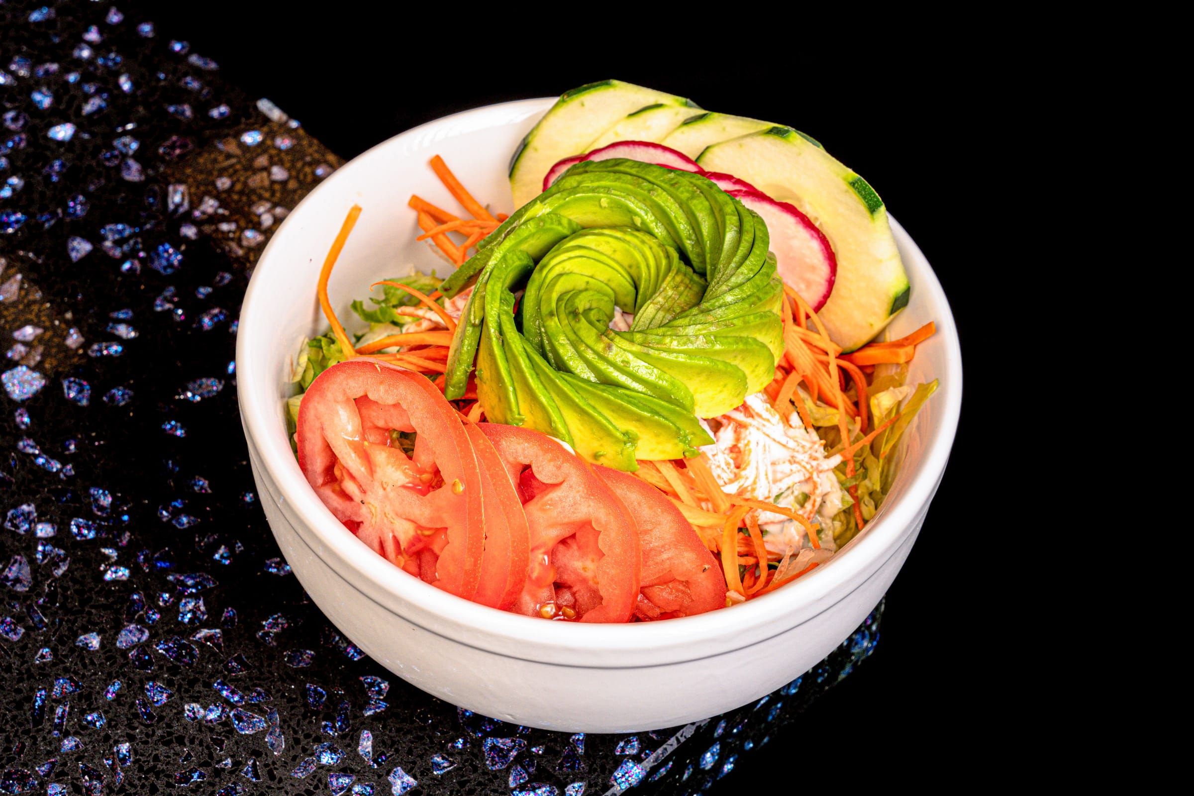 Fresh salad bowl with avocado, tomato, and carrot