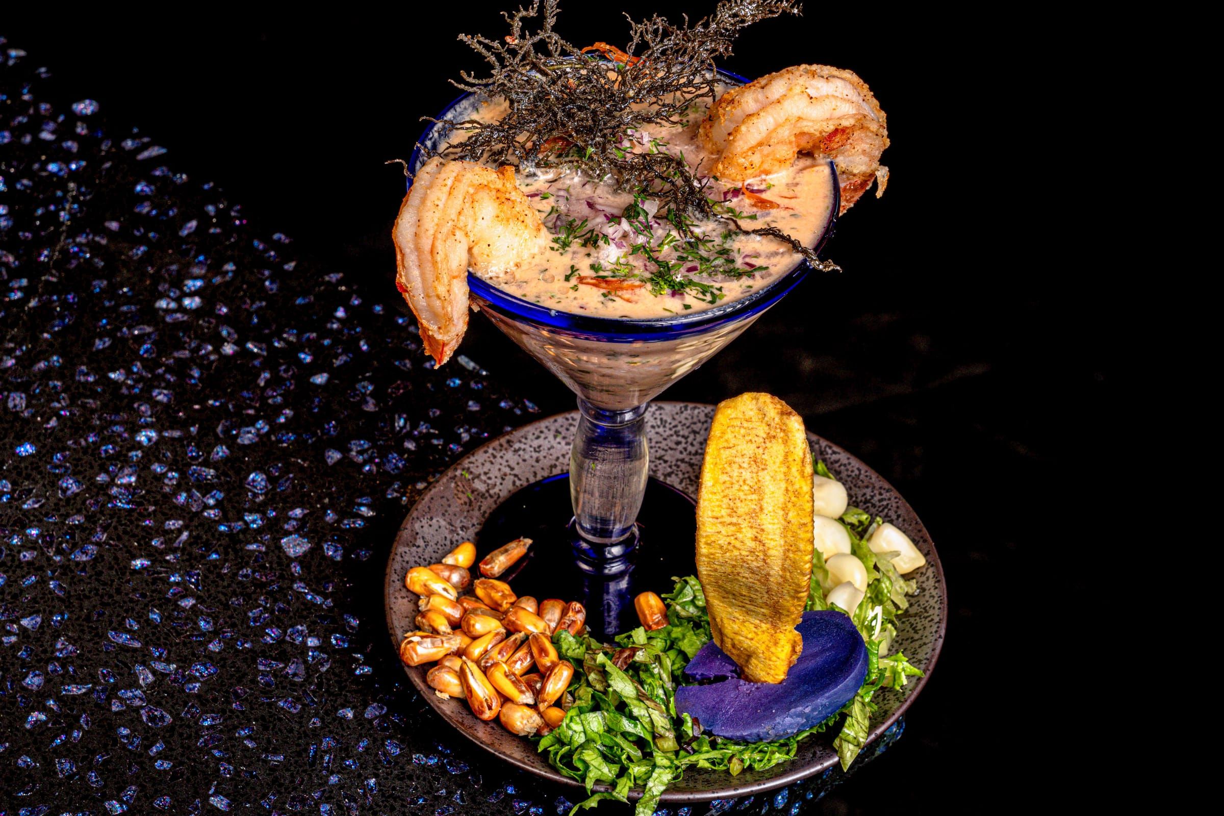 Glass of leche de tigre with seafood and cancha corn