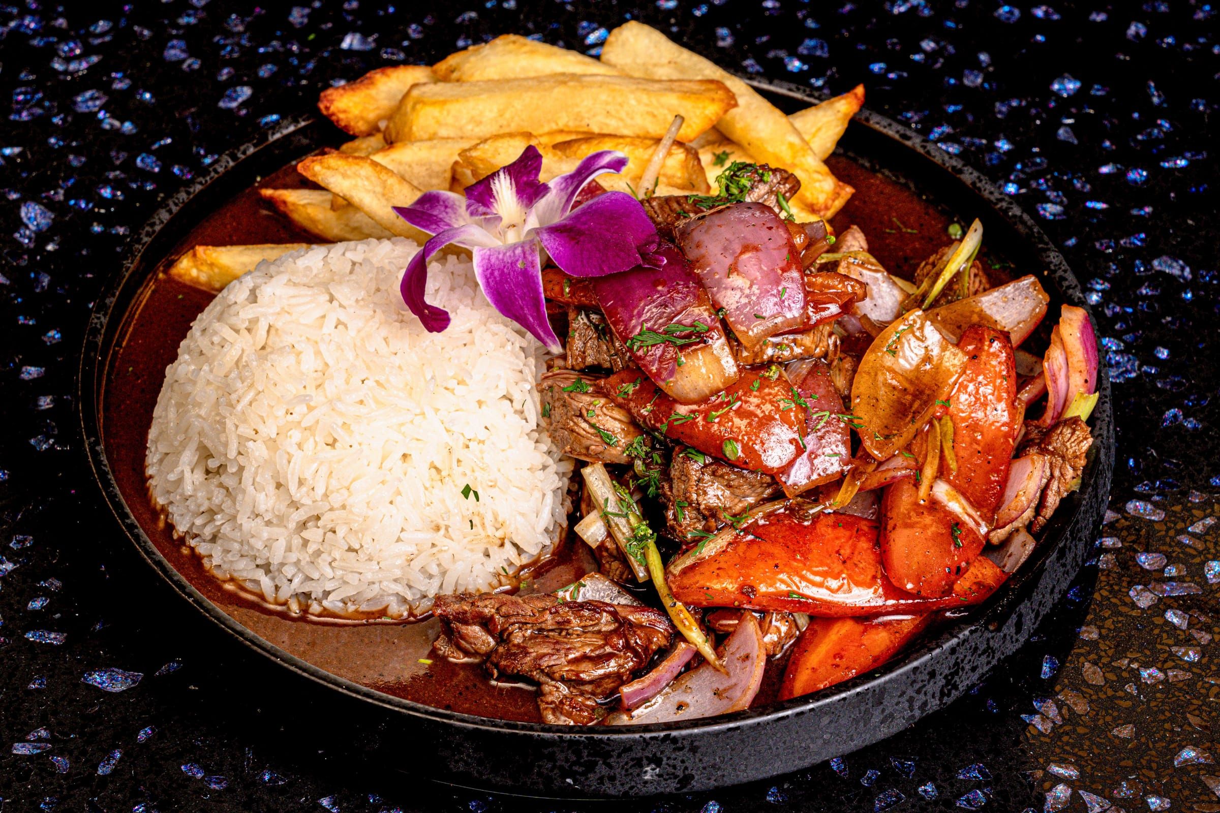 Lomo saltado, wok-seared beef with red onion and tomato over fries